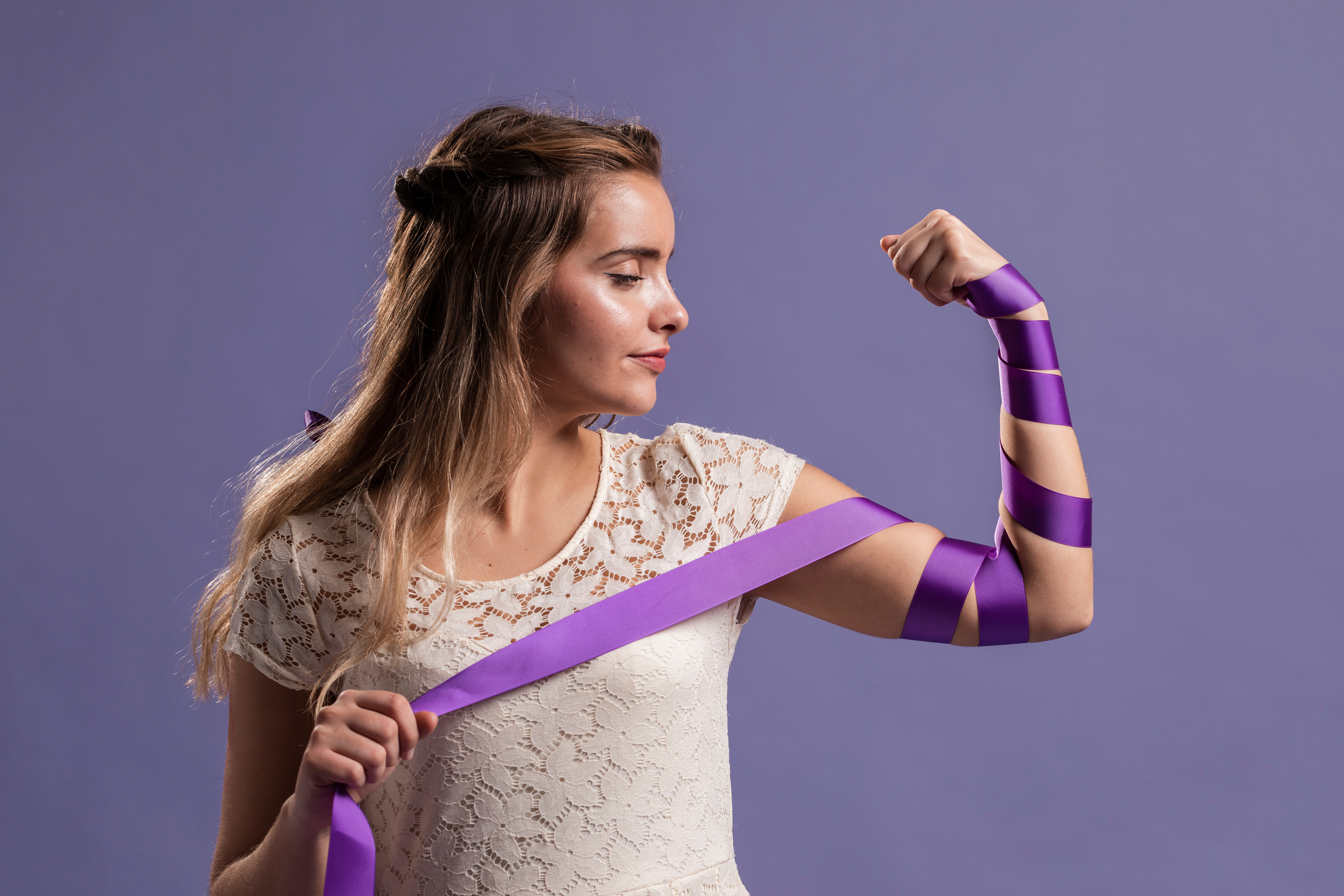 woman flexing her arm with ribbon as sign empowerment