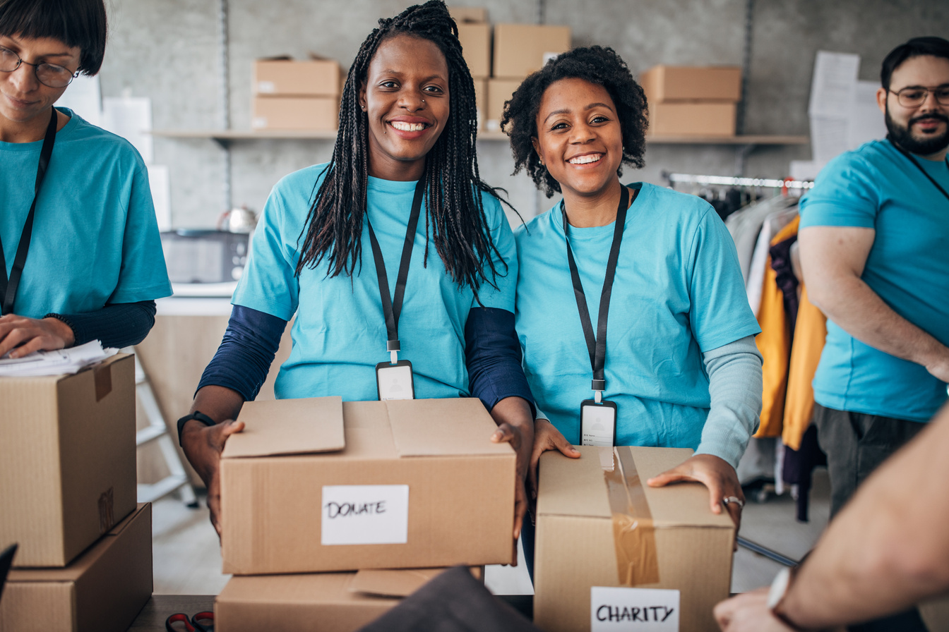 Black women volunteer packing donation boxes in charity food bank
